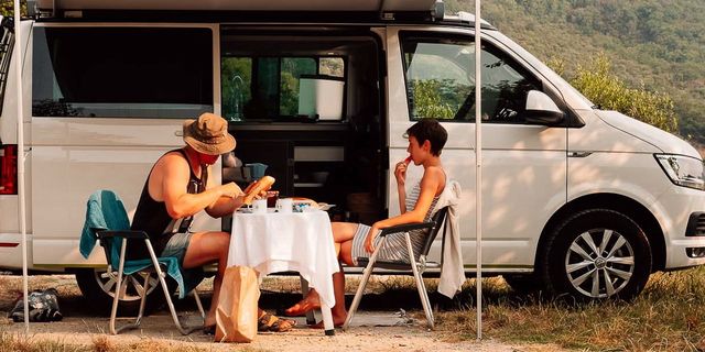 Paar vor Camper beim Frühstücken