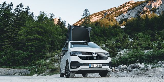 Ein VW California Van steht geparkt vor einer Bergkulisse.