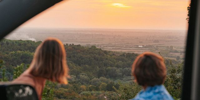 Zwei Freund:innen sitzen vor ihrem Camper und betrachten den Sonnenuntergang über Albanien bei ihrer Albanien Rundreise.