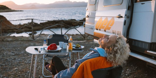 Frau genießt Sonne vor dem Camper