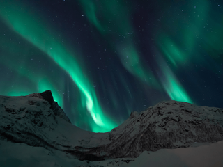 Nächtlicher Blick auf einen mit Schnee bedeckten Berg und Nordlichter am Himmel