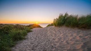 Sonnenuntergang am Meer hinter den Dünen am Strand in Zandvoort in Holland