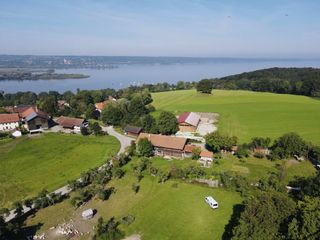 Eine Luftaufnahme mit Blick auf den Ammersee, Felder und Bauernhöfe.