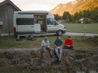 Beim Urlaub im Oktober sitzen drei Kletterfreunde vor einem Grand California Camper und machen Brotzeit.