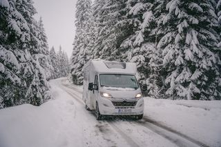 Ein Mooveo Wohnmobil fährt durch einen verschneiten Wald.