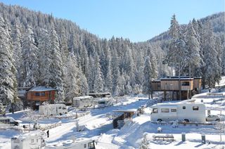 Der verschneite Caravan Park Sexten mit ein paar Campern und Hütten.