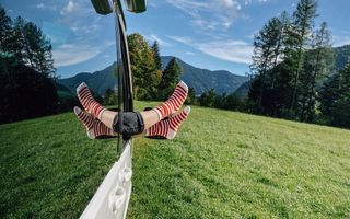 VW Ocean steht in idyllischer Berglandschaft man sieht Füße in roten Ringelsocken die aus dem Beifahrerfenster herausgestreckt werden