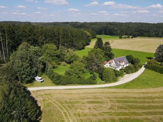 Luftaufnahme von einem Camper, der zwischen einem Wald und einem Feld steht.