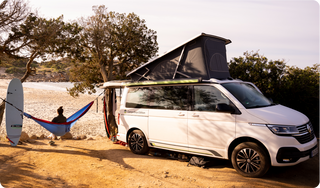 VW California am Strand mit Frau in Hängematte