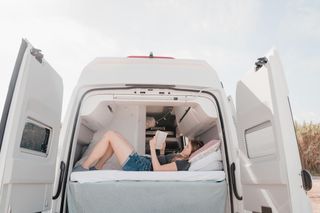 Frau liest im Campervan Bett ein Buch