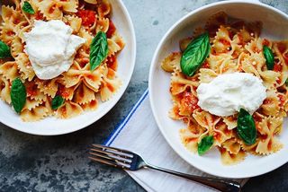 Zwei Teller gefüllt mit Fussili, Tomatensauce, Mozzarella, Basilikum und Parmesan