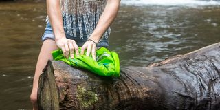 Eine Frau steht im Fluss und wäscht ihre Wäsche mit einem Washbag. 