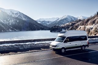 VW Grand California auf Bergstraße in winterlichem Alpenpanorama 